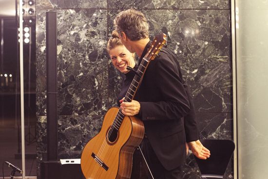 Katharina Gruber und Christian Gruber schauen sich an der Wand des Mies van der Rohe Pavillons lächelnd an