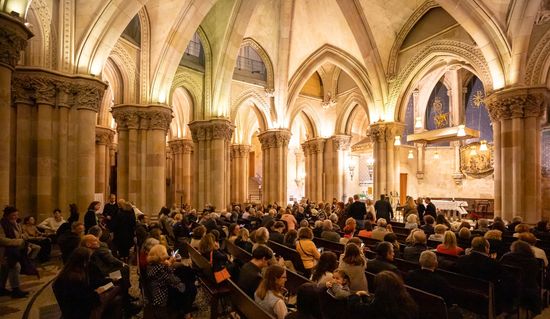 Die Krypta der Basilika Sagrada Família, fotografiert vom Eingangsbereich aus, mit allen Plätzen voll besetzt, kurz vor Beginn des Konzerts