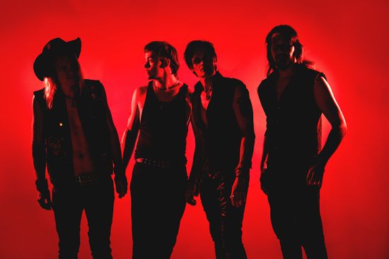 Die Band in einer Auto Werkstatt, Instrumente in der Hand, ein Oldtimer im Hintergrund