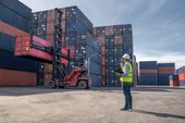 Ein Mann steht vor einer großen Menge an gestapelten Containern