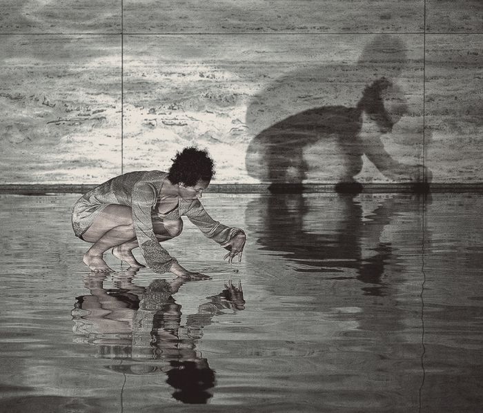 Bailarina se detiene en un movimiento en el agua, evento de danza en el Pabellón Mies van der Rohe, Barcelona